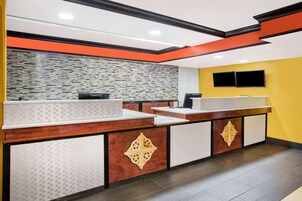 Un área de recepción con diseño moderno, que presenta un patrón de piso a cuadros, un salpicadero de azulejos y un mostrador de madera con detalles decorativos.