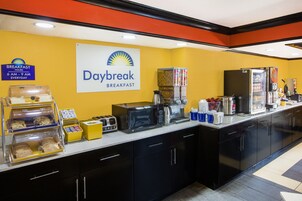 Un área de desayuno con un cartel que dice Daybreak Breakfast, una cafetera, un microondas y diversos alimentos.