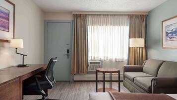 Una habitación de hotel con escritorio, silla de oficina, sofá y cama.