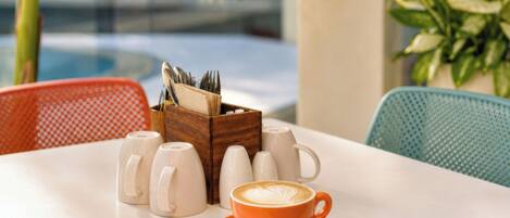A table with a coffee cup, sugar cubes, and a napkin holder.