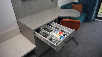 A compact living space with a built-in TV, a sofa, a dining table, and a storage drawer with various items.