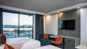 A hotel room with two beds, a desk, a TV, and a view of a parking lot and hills. - Millennium Hotel Rotorua (Rotorua)