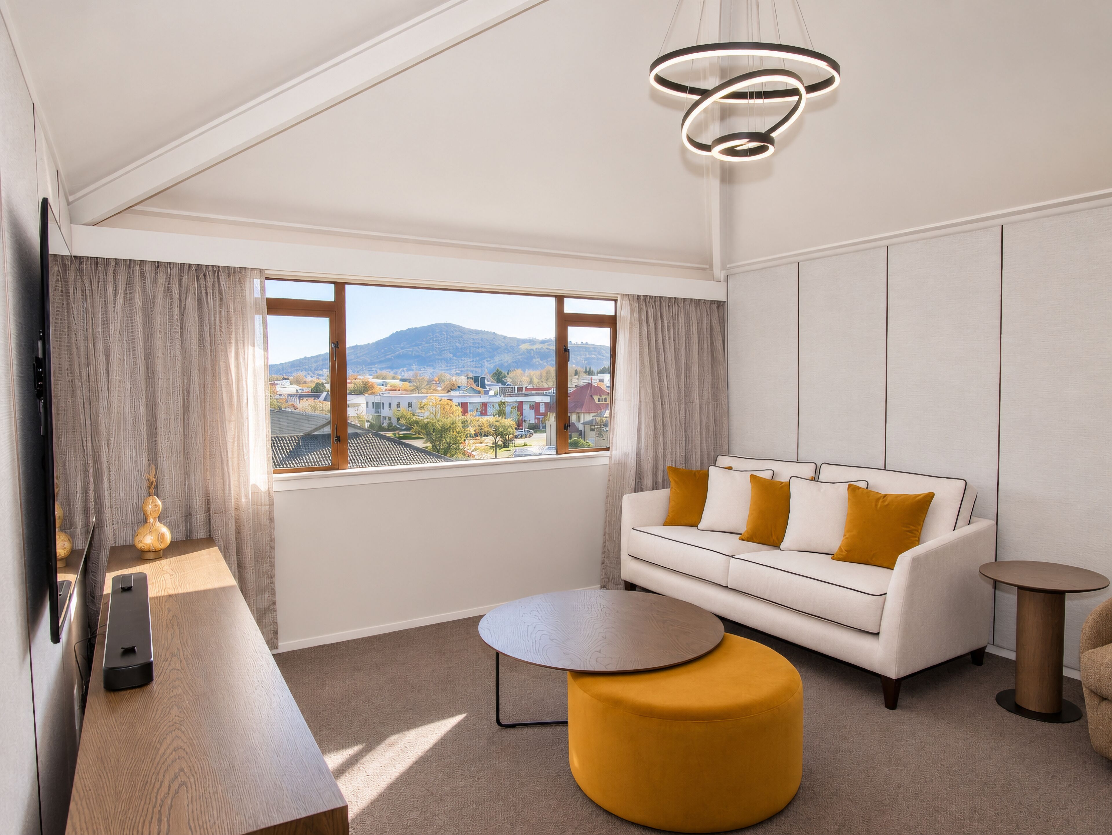 A modern living room with a sofa, ottoman, and a round table.