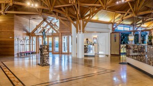 A spacious lobby with a high wooden ceiling, a reception desk, and a marble pillar.