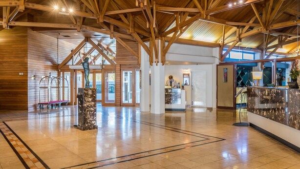A spacious lobby with a high wooden ceiling, a reception desk, and a marble pillar. - Millennium Hotel Rotorua (Rotorua)