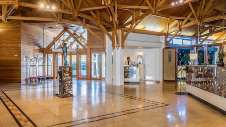 A spacious lobby with a high wooden ceiling, a reception desk, and a marble pillar.