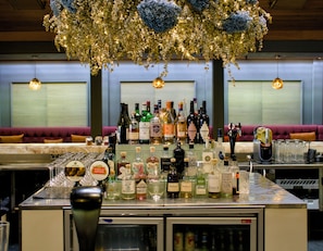 A bar area with a variety of liquor bottles, glasses, and a decorative hanging plant.