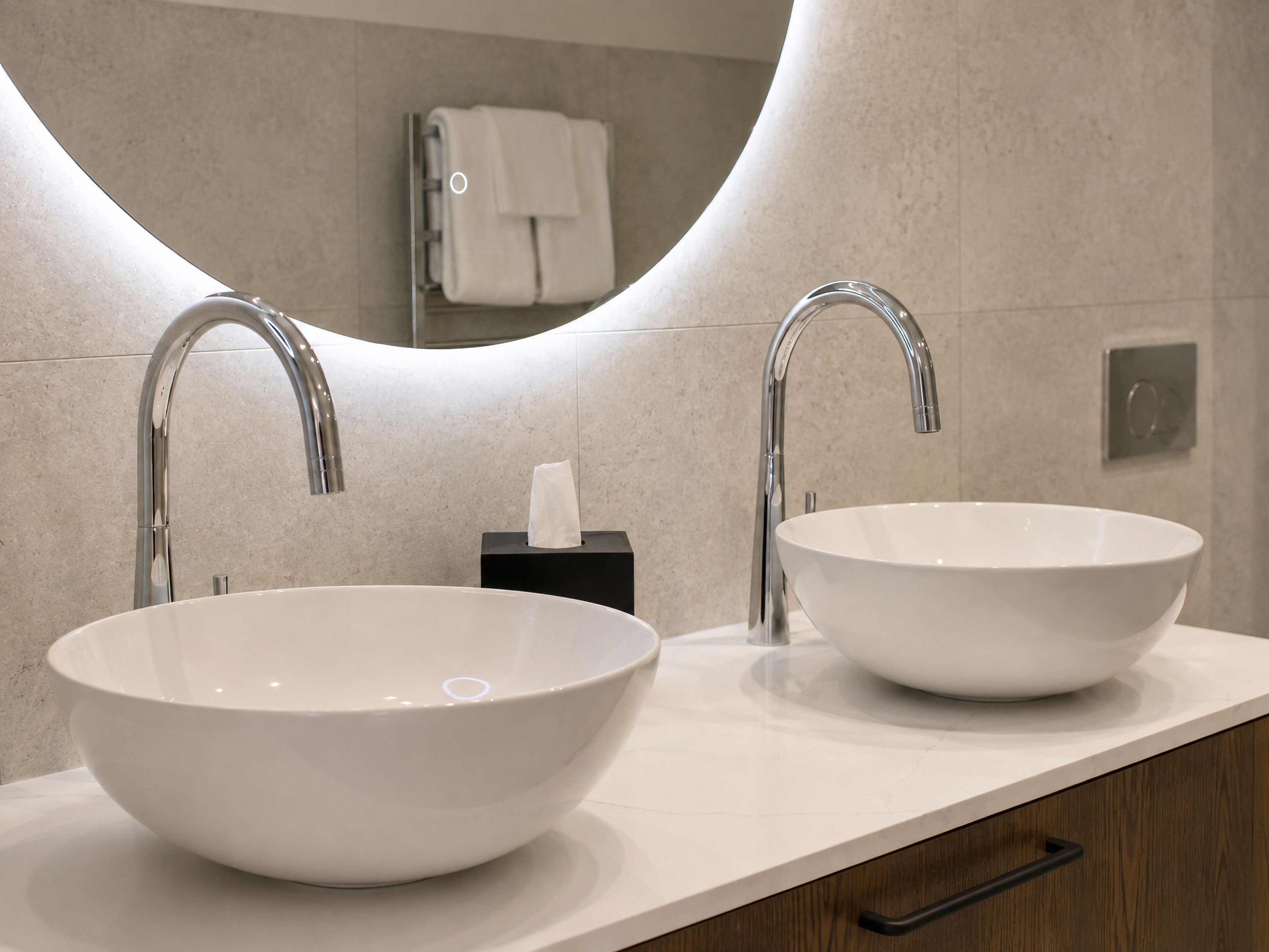 A bathroom with two vessel sinks, a mirror, and a towel rack.