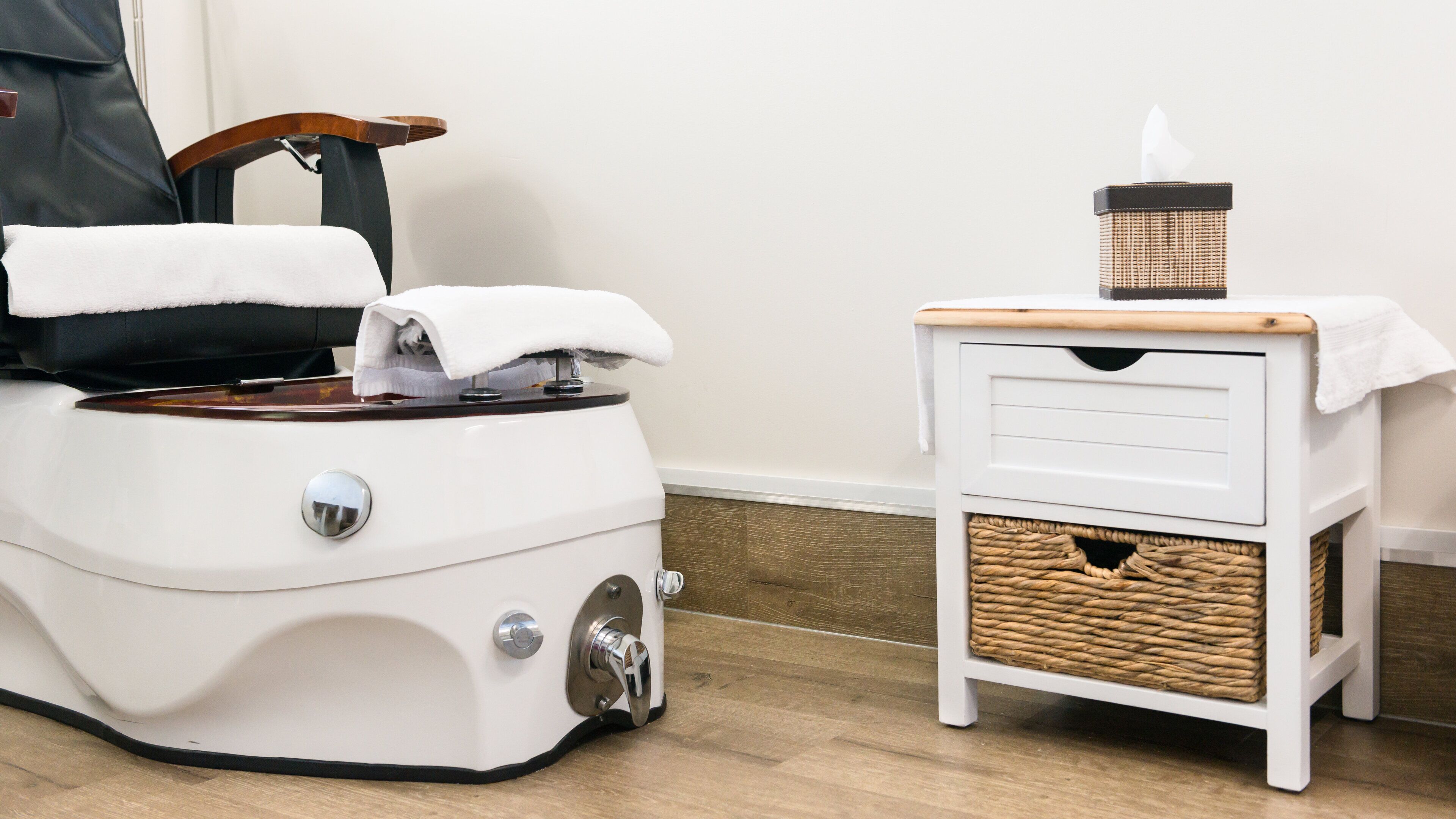 Une salle de bain moderne avec un poêle électrique blanc, un petit meuble blanc agrémenté de paniers en osier et une chaise en bois.