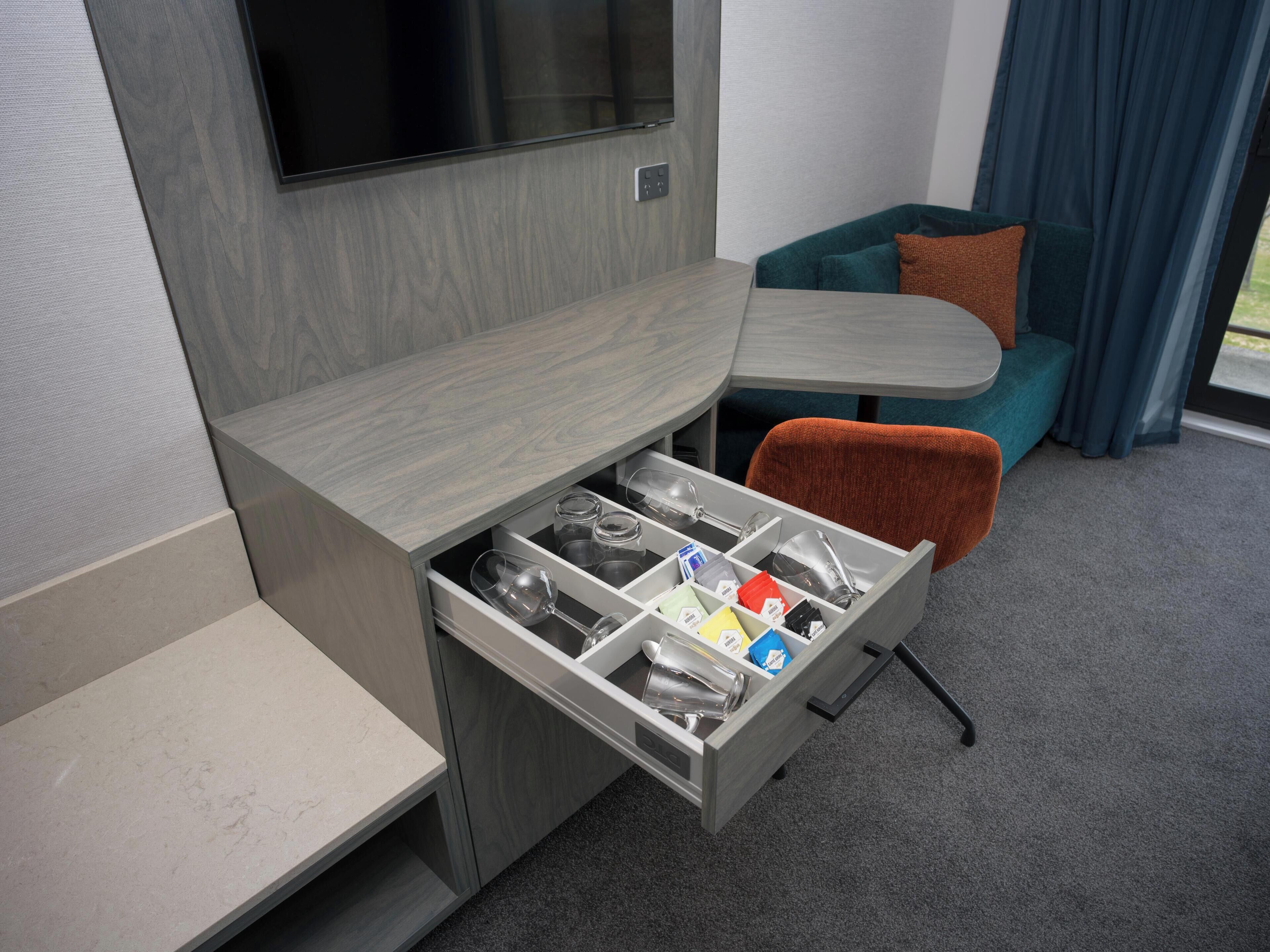 A compact room with a built-in TV, a small dining table, and a cozy seating area with a sofa and a chair.
