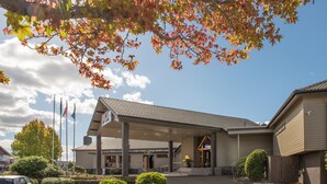 A building with a covered entrance, flags, and a clear sky. - Millennium Hotel Rotorua (Rotorua)