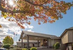 A building with a covered entrance, flags, and a clear sky.