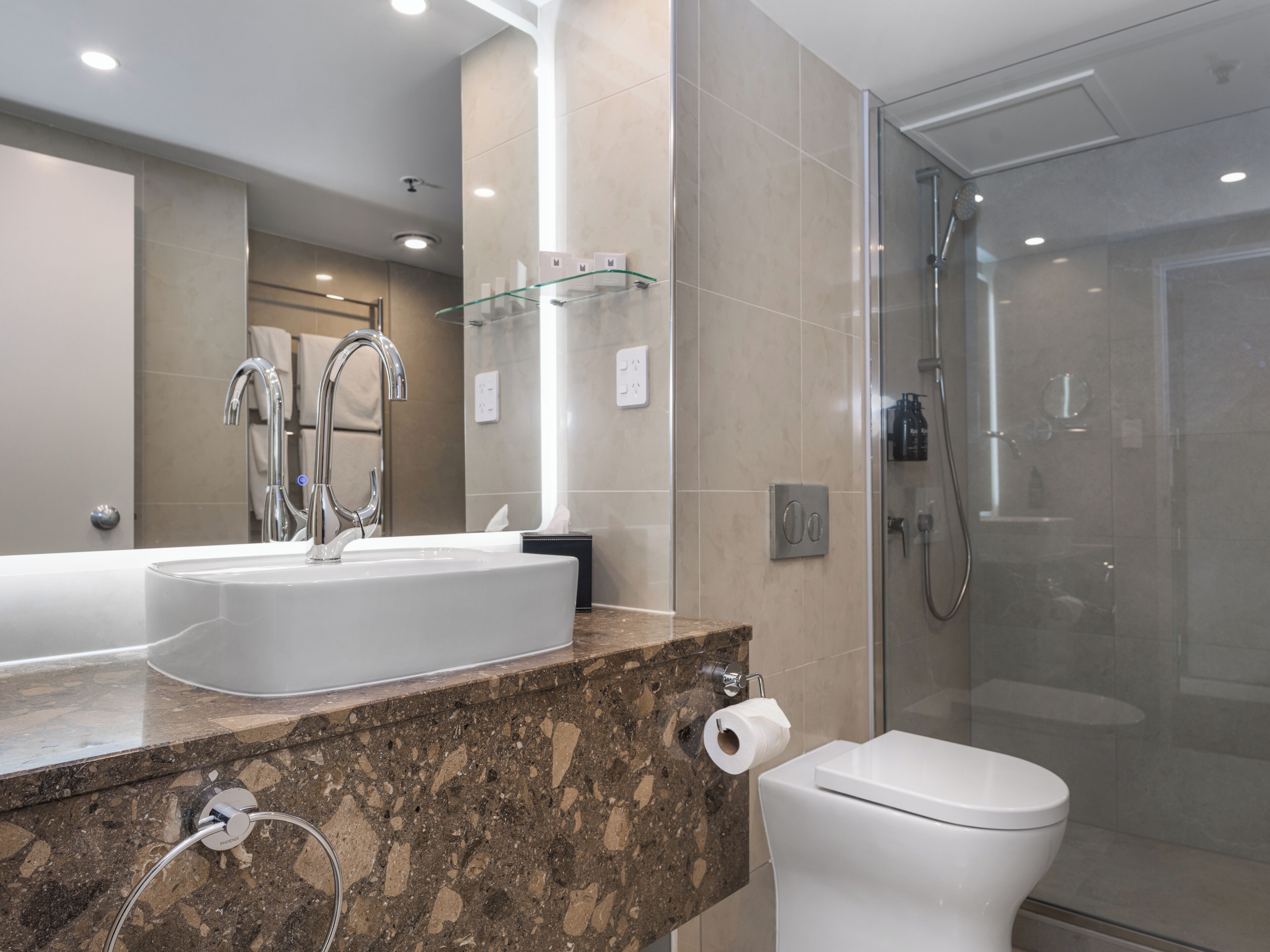 Un baño moderno con un lavamanos grande, un espejo y una ducha con mampara de vidrio.
