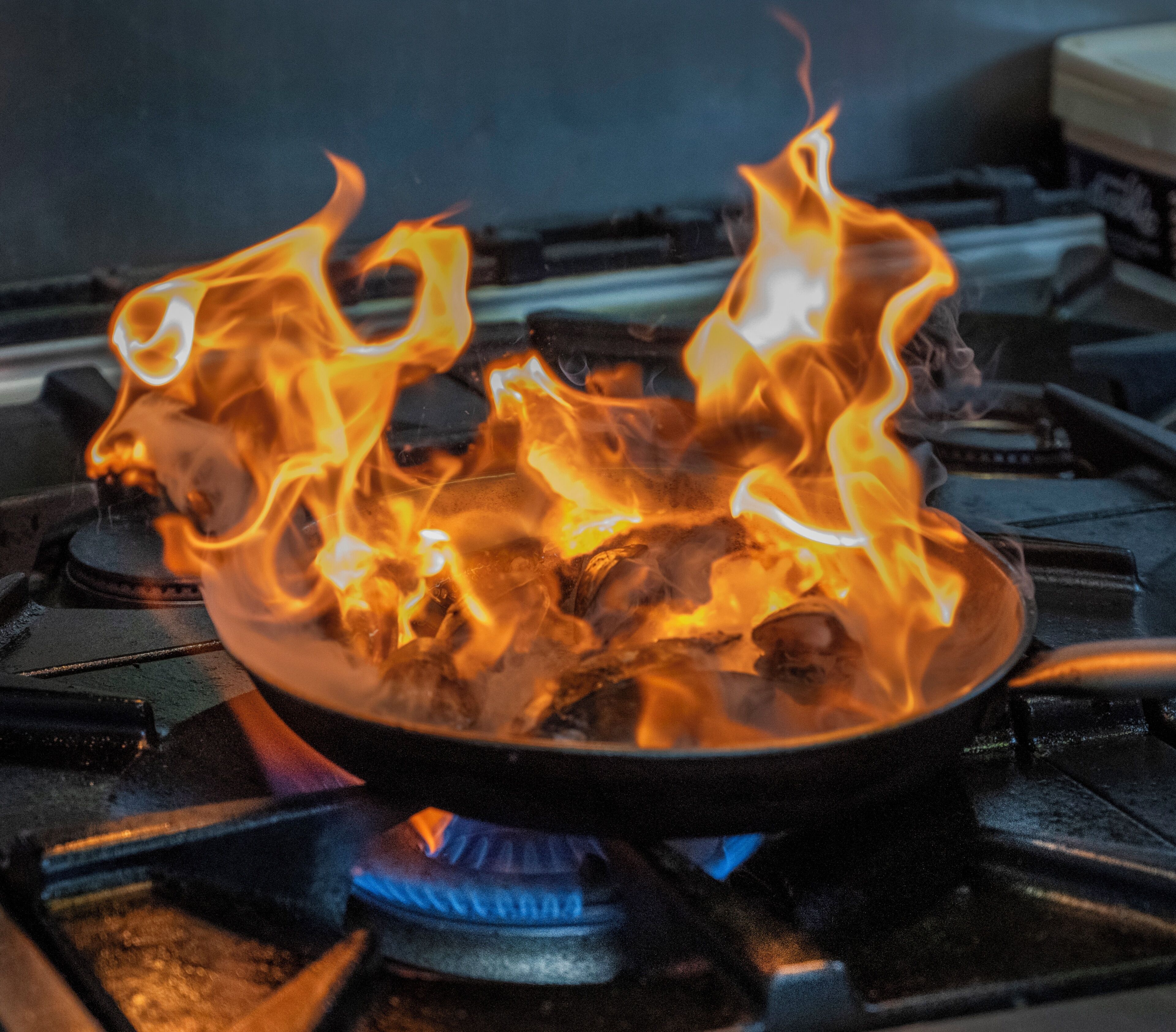 A gas stove with a pan on it, flames are visible.
