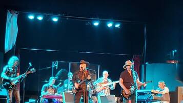 A band performing on a stage with various musical instruments and a laptop.