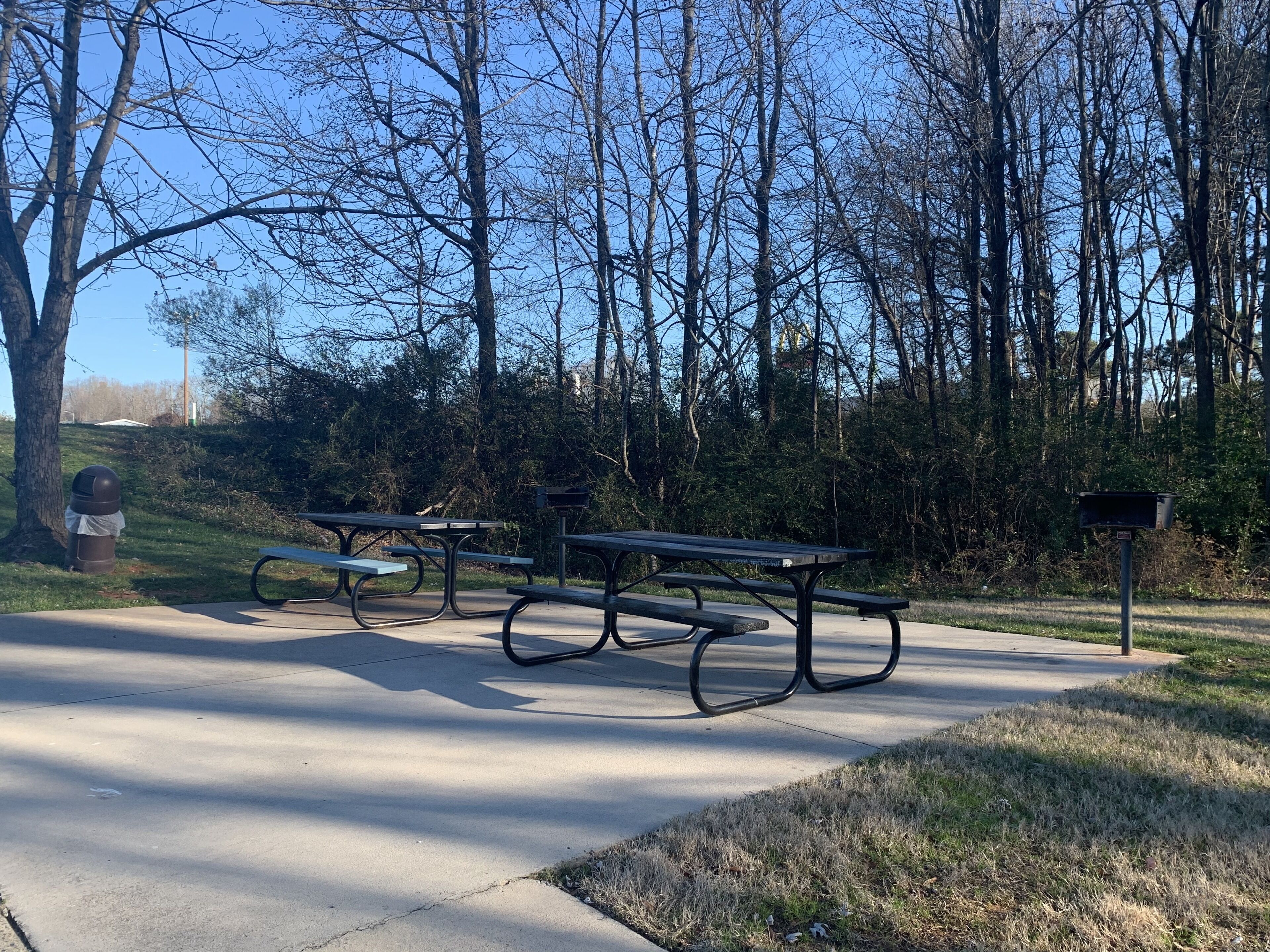 Un parc équipé de tables de pique-nique, d’une poubelle et d’une boîte aux lettres.