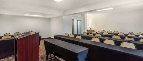 A conference room with a podium, rows of tables, and chairs.