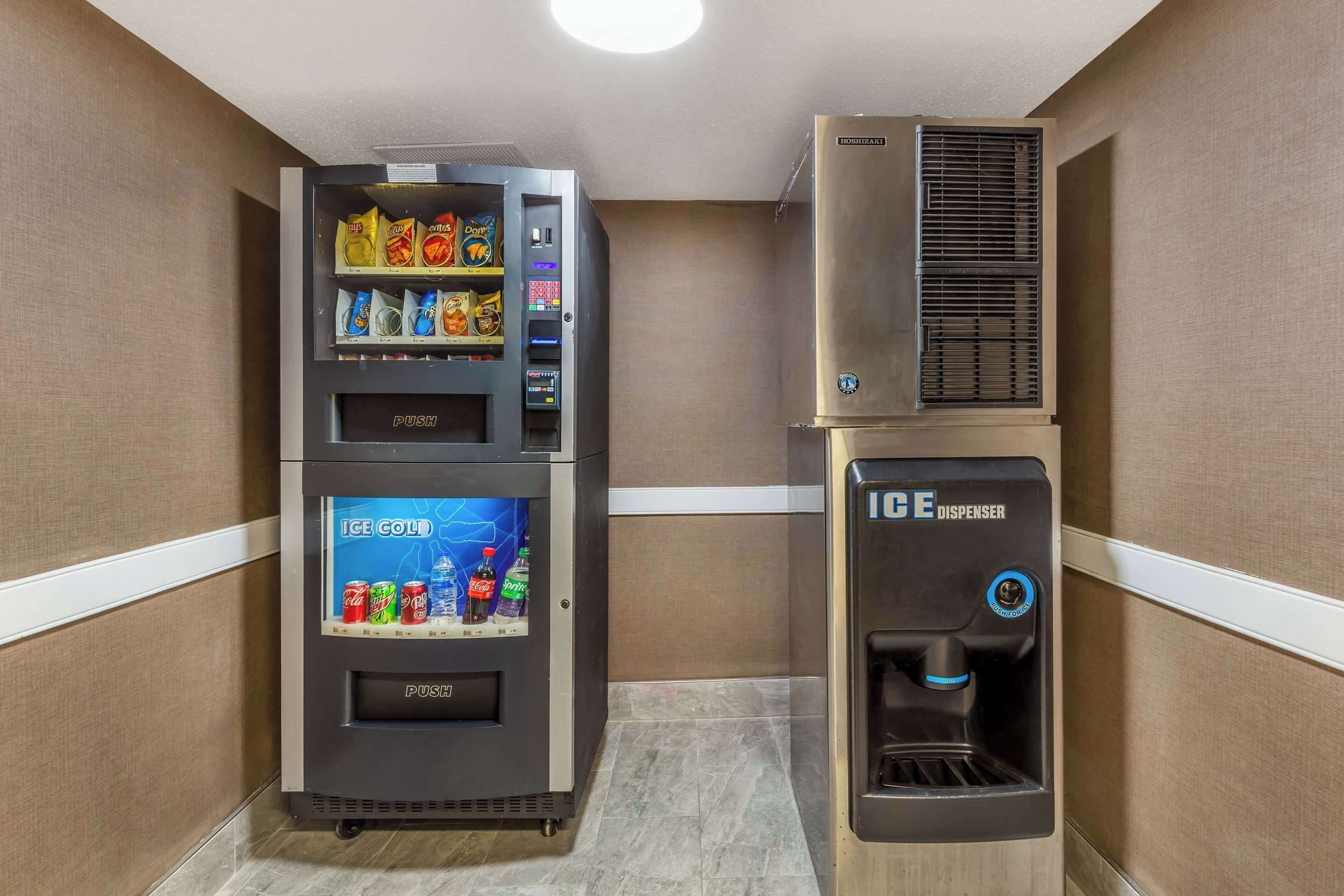 Máquina expendedora con aperitivos y bebidas, un botón para hielo y un dispensador de agua.