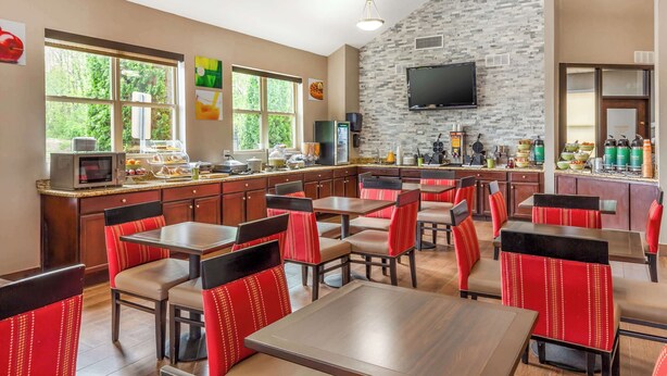 A restaurant with a stone wall, a flat-screen TV, and a buffet area. - Quality Inn Asheboro South (Asheboro)