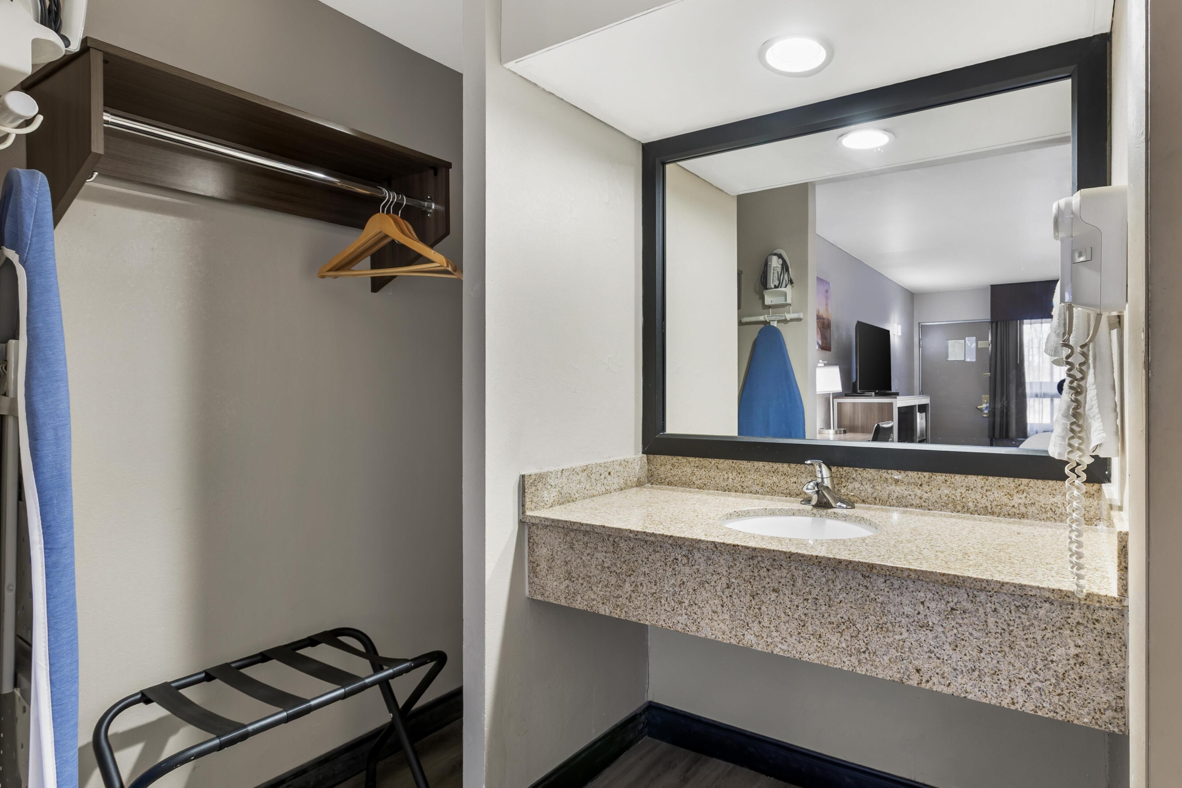 A bathroom with a sink, mirror, towel rack, and a shower area.