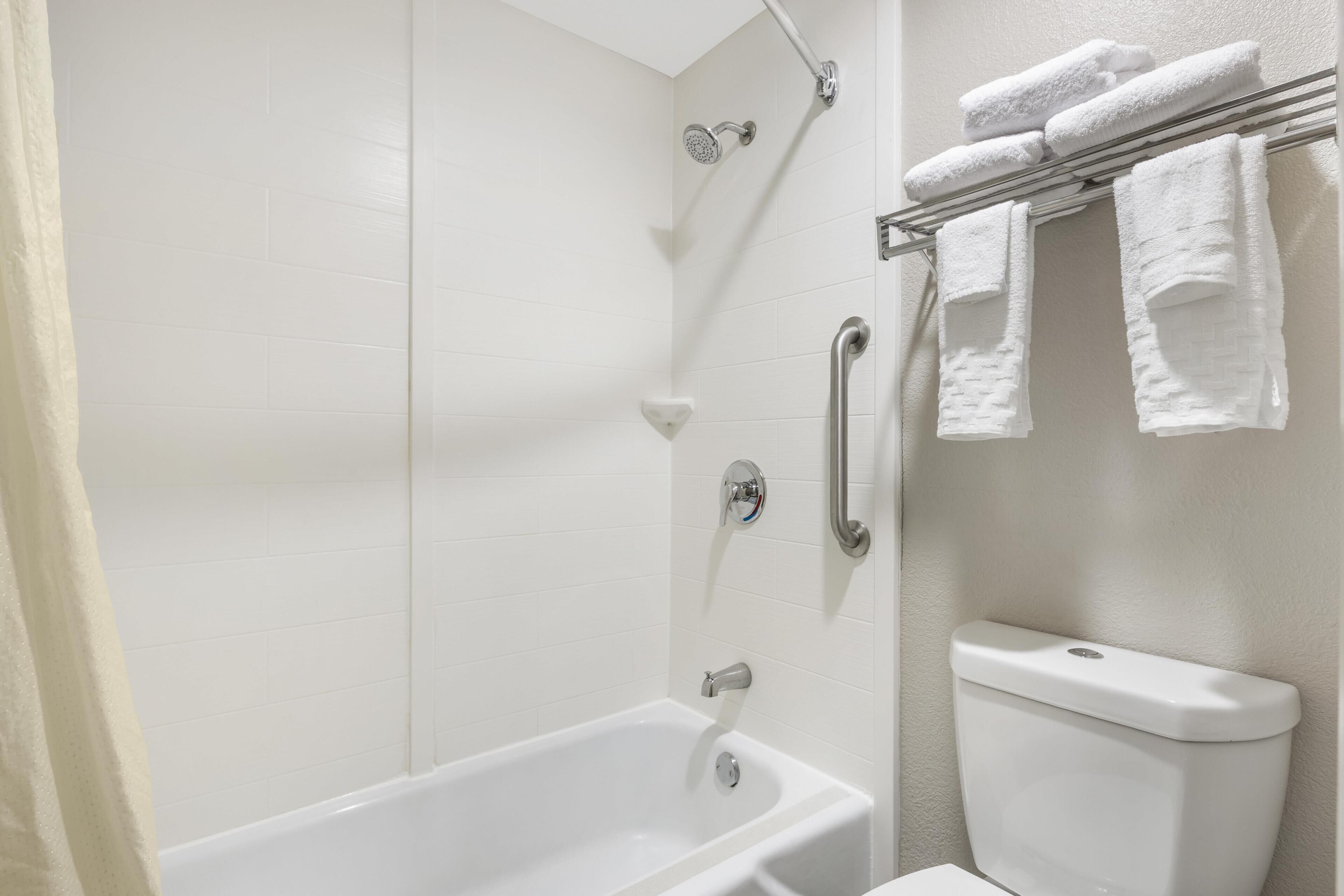 A bathroom with a bathtub, shower, toilet, and towel rack.