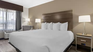 A hotel room with a large bed, bedside tables with lamps, a chair, and a window with curtains.