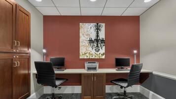 A conference room with two desks, two chairs, a printer, and a chandelier.