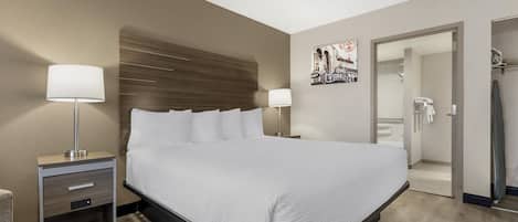 Una camera d'albergo moderna con un letto grande, lampade sui comodini, una testiera in legno, un'opera d'arte appesa al muro e un armadio a tutta parete.