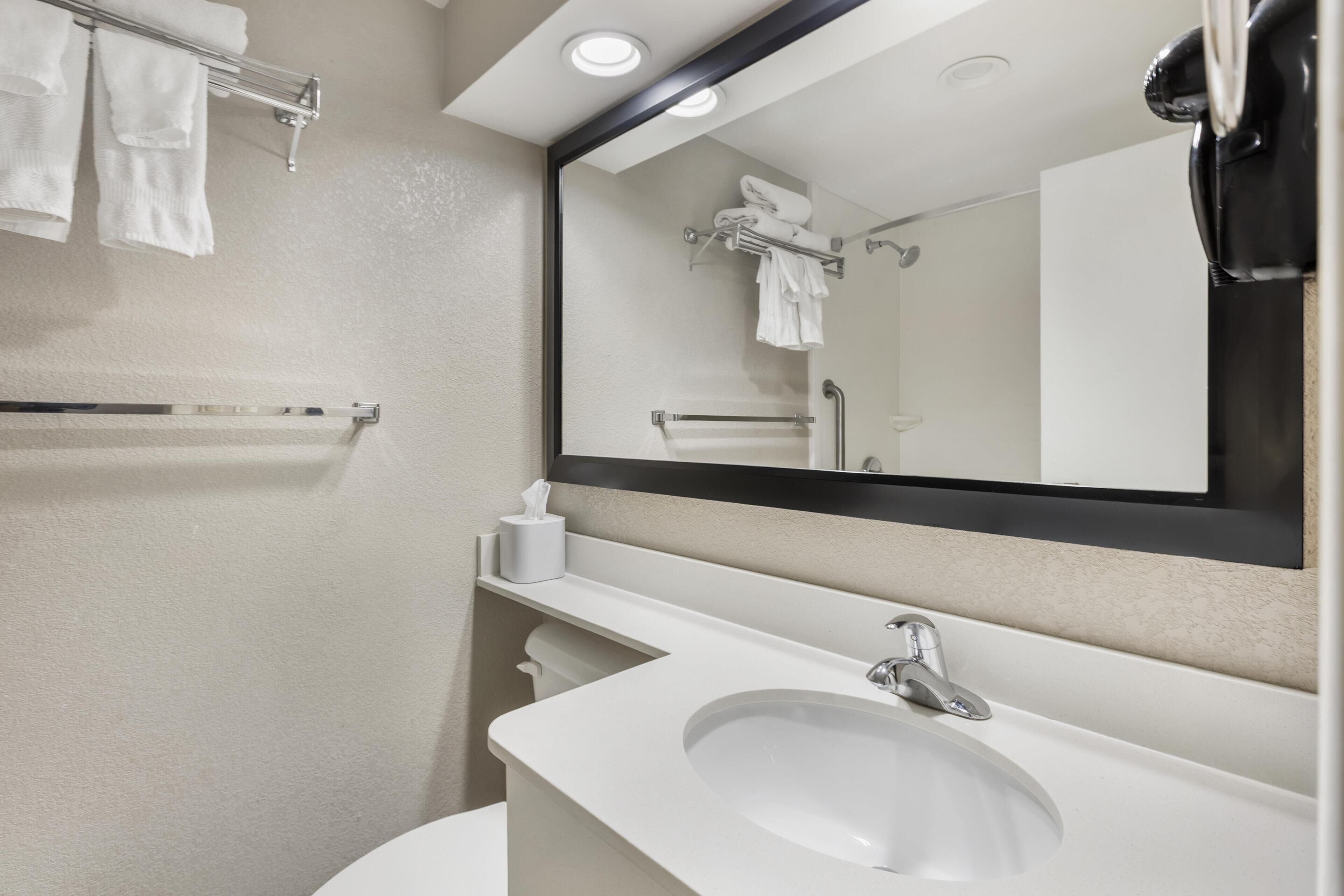 A bathroom with a white sink, a mirror, and a towel rack.