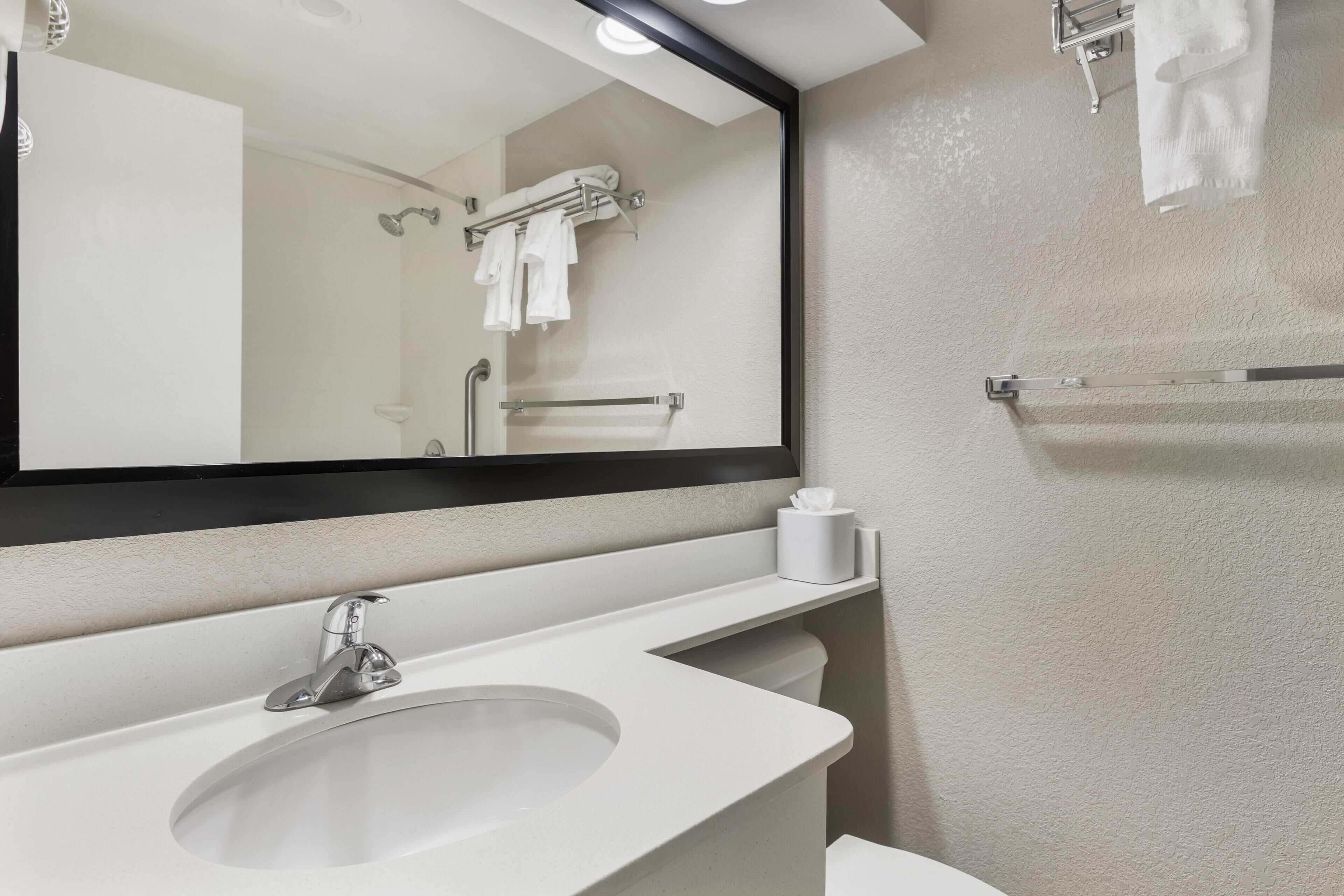 Une salle de bain équipée d’un lavabo, d’un miroir, d’un porte-serviettes et de toilettes.