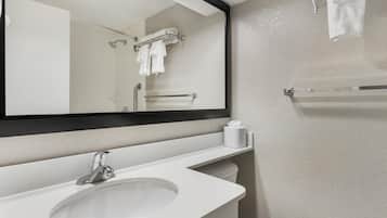 Un baño con lavamanos, espejo, toallero y retrete.