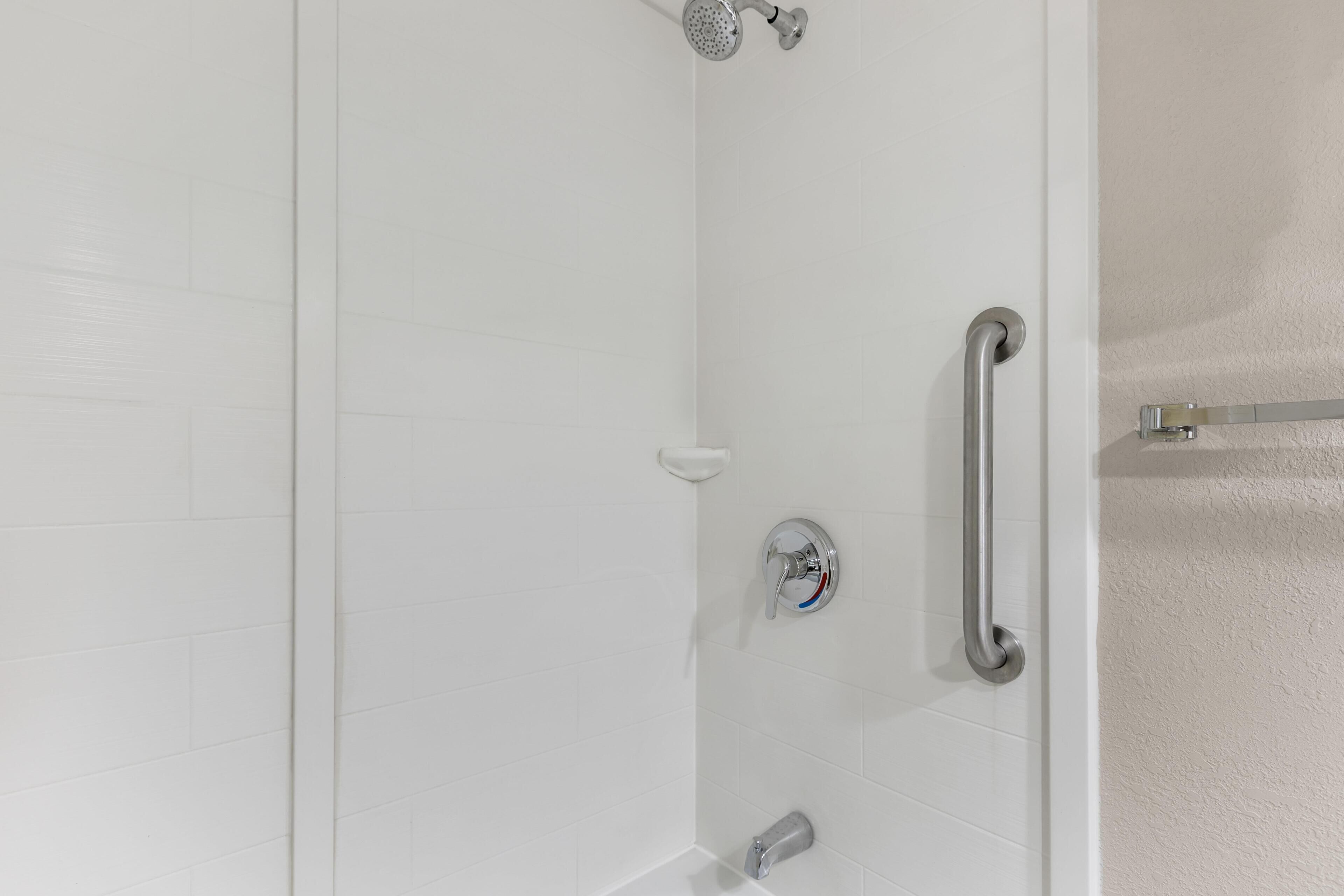 A shower with a handheld showerhead, a handheld showerhead, and a handheld showerhead.