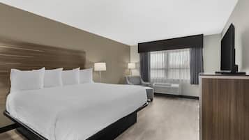 A hotel room with a large bed, a desk, a chair, a TV, and a window with curtains.