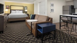 Een hotelkamer met een bed, een bank, een tafeltje, een bureau, een koelkast en een televisietoestel.