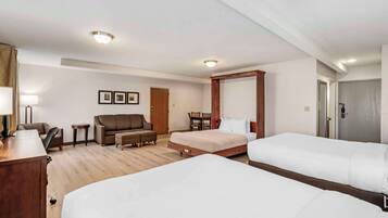 A hotel room with two beds, a sofa, a desk, and a chair.