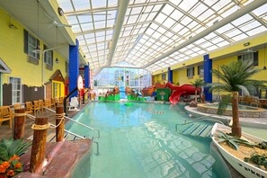 An indoor swimming pool with a glass ceiling, slides, and a play area.