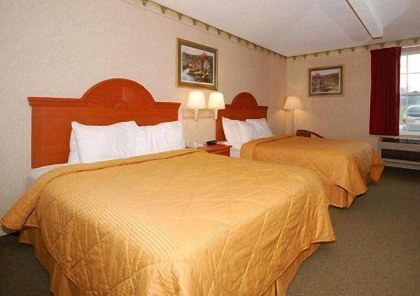 Een hotelkamer met twee bedden, elk met hoofdeinde en nachtlampjes.