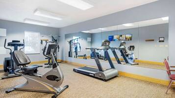 A gym with cardio machines, mirrors, and exercise equipment.