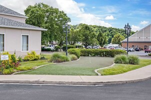 A building with a parking lot, a lawn, and a sign indicating a green space for guests.