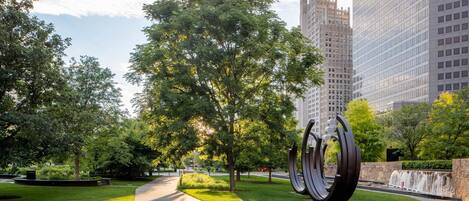A park with a pathway, trees, and a modern sculpture.