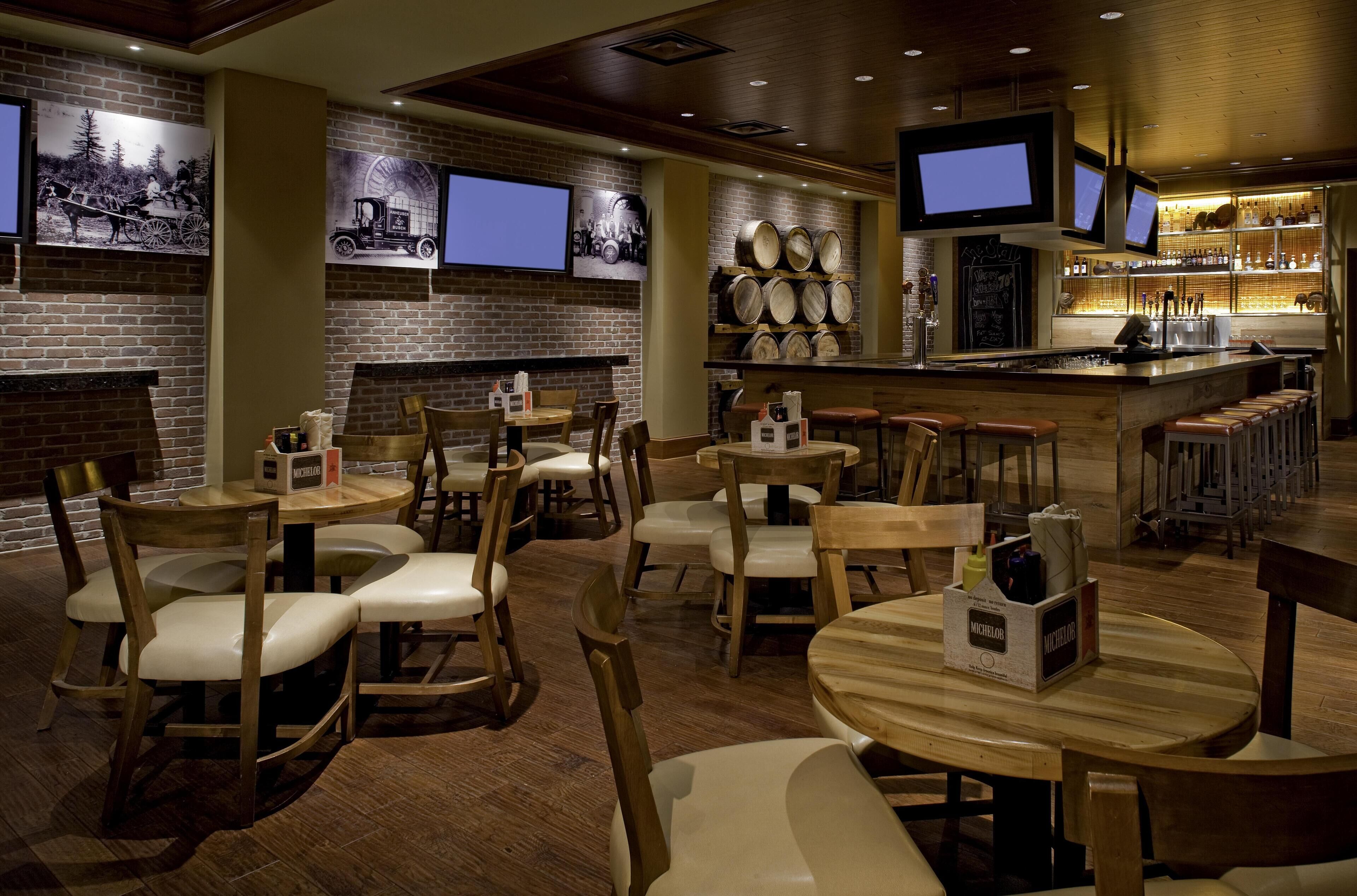 Ein Restaurant mit Ziegelwänden, Holztischen und -stühlen sowie einer Theke mit einem Fernseher.