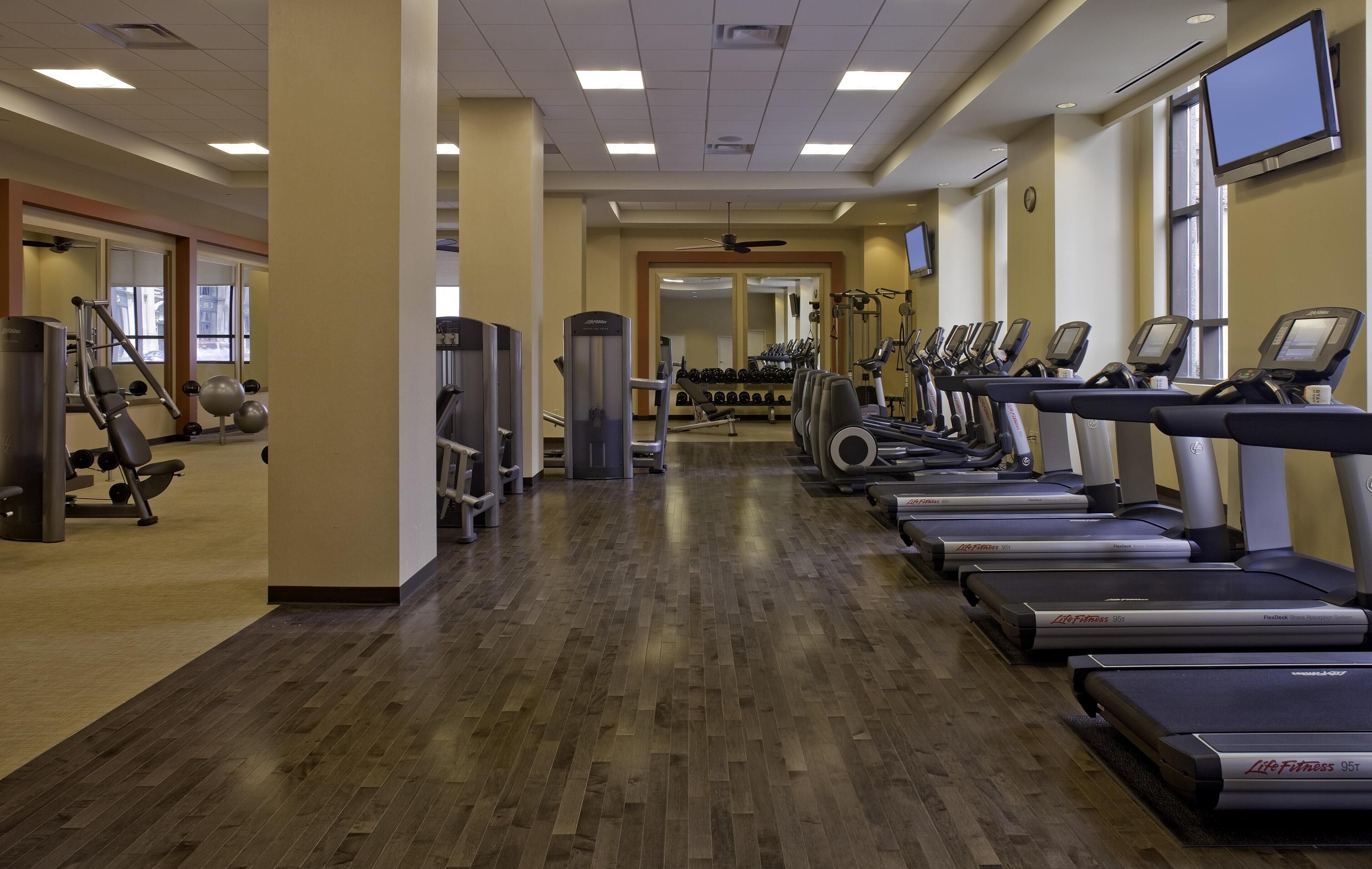 Une salle de sport équipée de tapis de course, d’appareils de musculation et de poids libres.