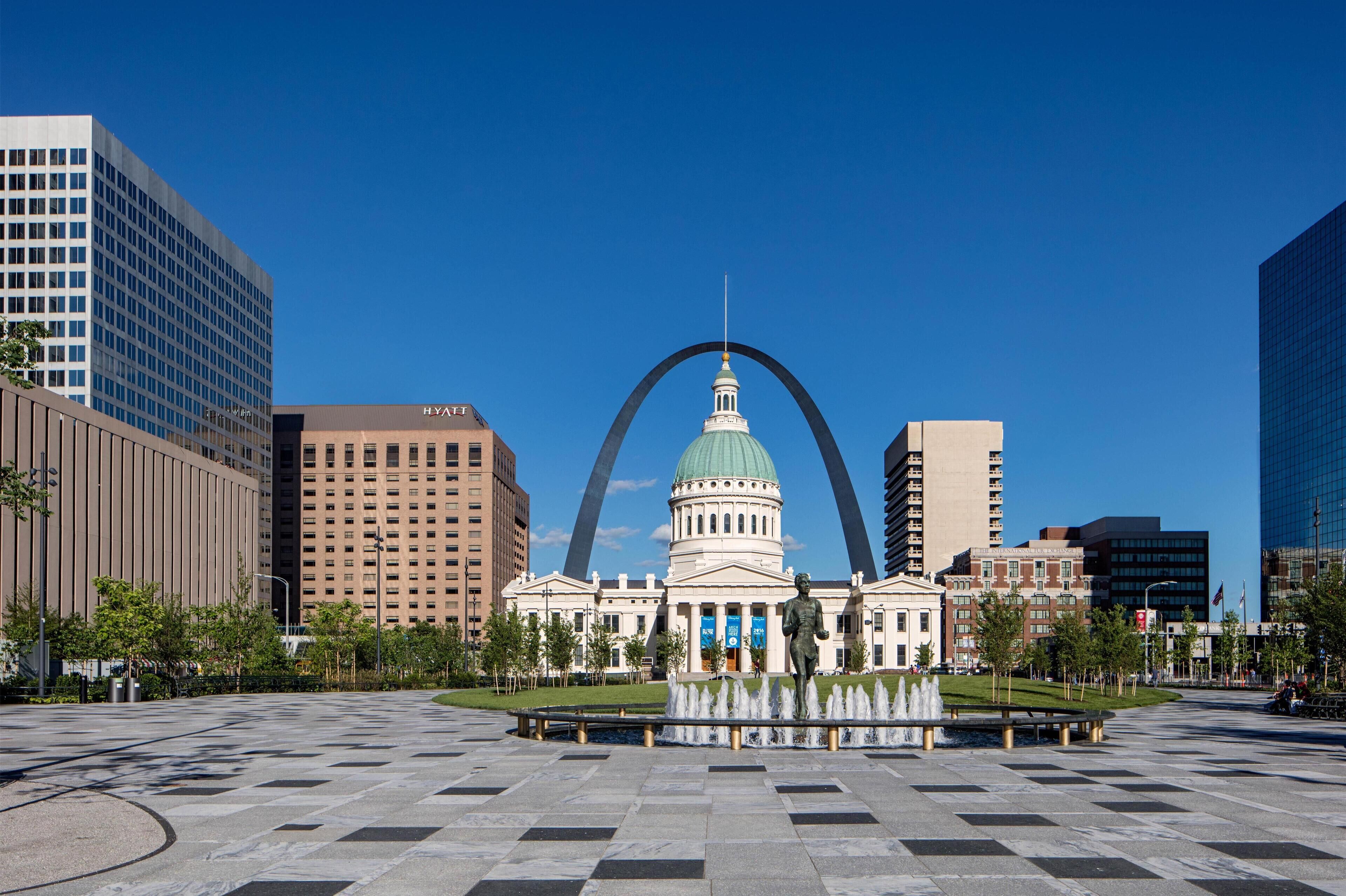 A large public square with a prominent building featuring a dome and a statue in the center.