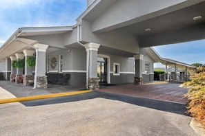 A hotel entrance with covered outdoor seating, stone pillars, and a paved walkway. - Quality Inn & Suites Greenville - Haywood Mall (Greenville)