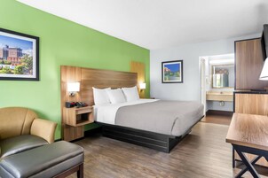 Una habitación de hotel con cama, escritorio, silla y televisor.