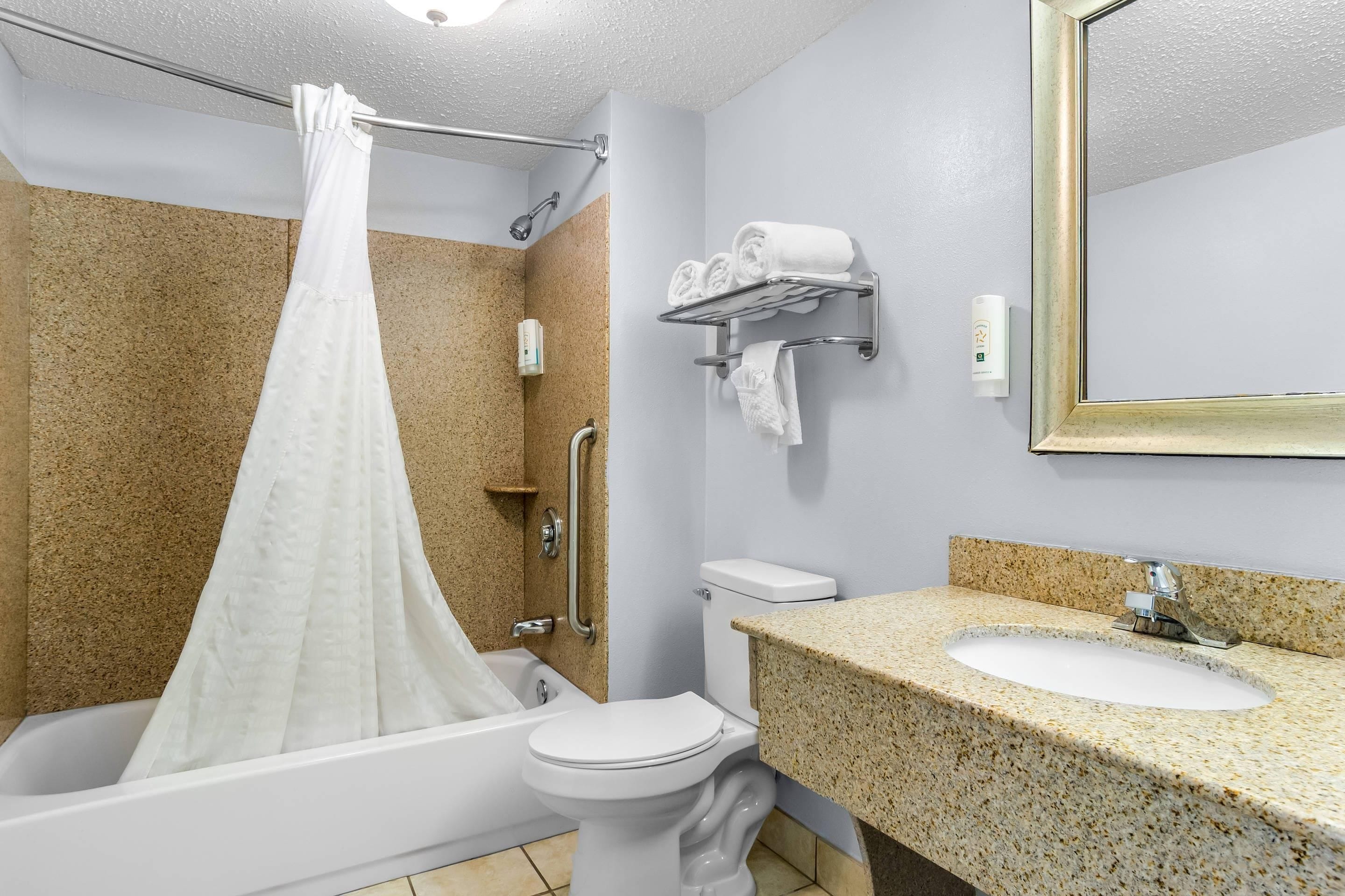 A bathroom with a bathtub, toilet, sink, and a shower curtain.