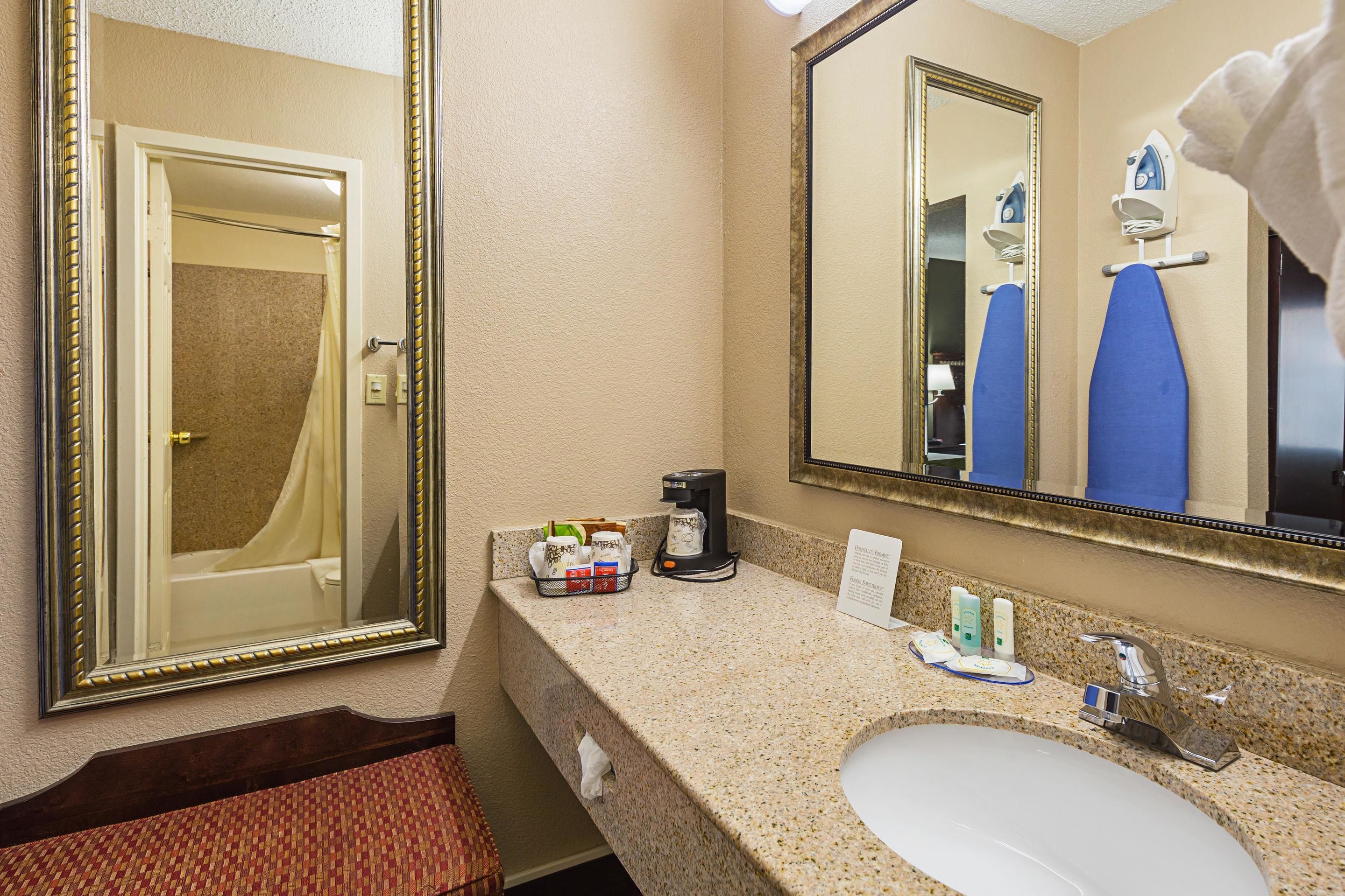 Une salle de bain d’hôtel équipée d’un lavabo, d’un miroir et d’articles de toilette.
