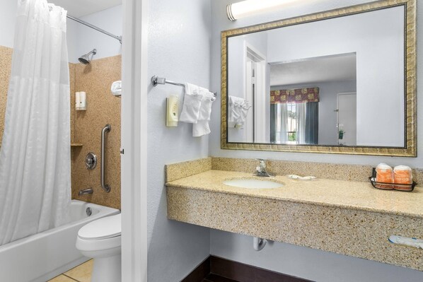 Un baño con ducha, inodoro, lavamanos y espejo.