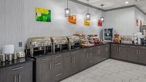A buffet setup with multiple food dispensers, a coffee station, and a refrigerator. - Quality Inn & Suites Greenville - Haywood Mall (Greenville)