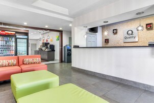 Zona de recepción con un refrigerador de Coca-Cola, mostrador con un letrero que dice 'Quality' y asientos con cojines de colores.